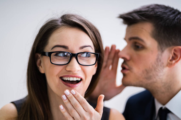 Close-up Of Businessman Whispering Into Female Partner's Ear - 写真・画像