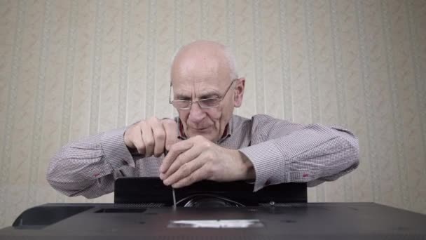 aged bald man unscrews outdated black television set cover - Video