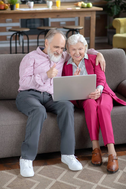 Elderly married couple sitting on the sofa and having video call - Photo, image