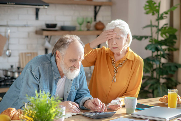 Elderly married couple making calculations together and looking disturbed - Foto, imagen