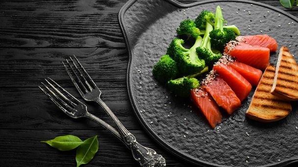 Brócoli y salmón salado. Alimento saludable para la dieta. En un plato de piedra negra. Vista superior
. - Foto, imagen
