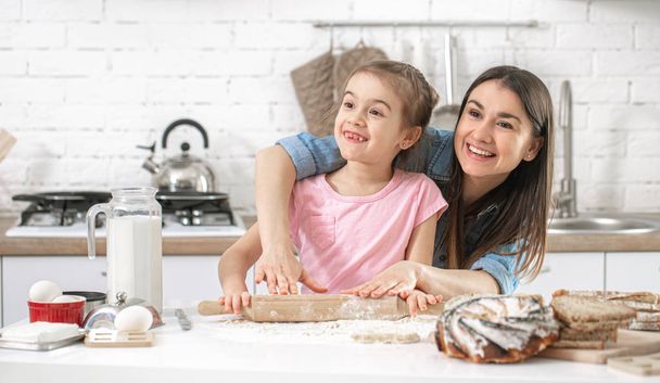 Boldog család. Anya és lánya süteményt készítenek a konyhában. A szerető család és családi értékek fogalma. Egészséges otthoni élelmiszer. - Fotó, kép