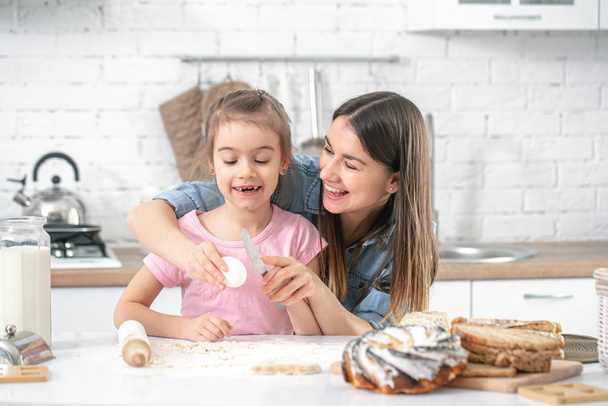 Happy family. Mom and daughter prepare pastries in the kitchen. The concept of a loving family and family values. Healthy home food. - Fotografie, Obrázek