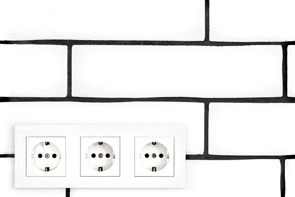 Prises électriques contre un mur de briques blanches. Espace pour le texte
. - Photo, image