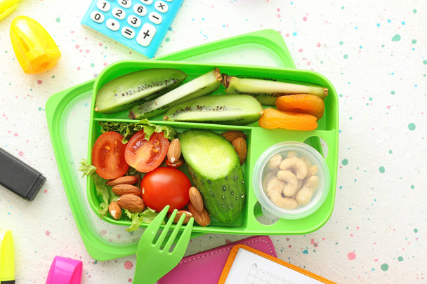 Scatola pranzo scuola con cibo gustoso e articoli di cancelleria sul tavolo
 - Foto, immagini