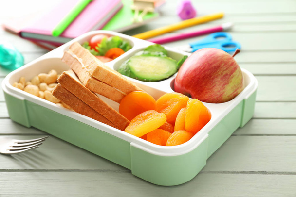 Scatola pranzo scuola con cibo gustoso in tavola
 - Foto, immagini
