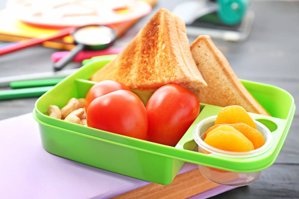 Boîte à lunch scolaire avec une nourriture savoureuse et de la papeterie sur la table
 - Photo, image