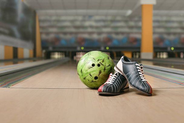 Bal en schoenen op verdieping in bowlingclub - Foto, afbeelding