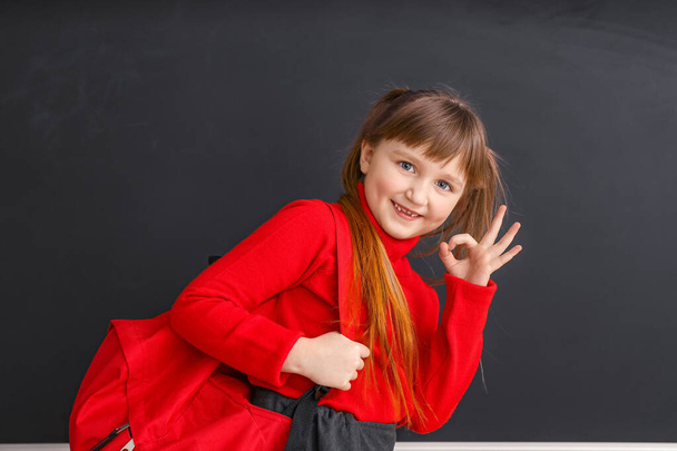 Nettes kleines Schulmädchen zeigt OK in der Nähe der Tafel im Klassenzimmer - Foto, Bild