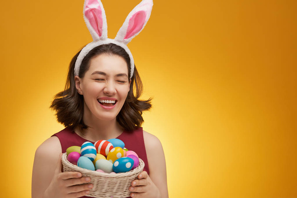 Happy Easter! Young woman with colorful eggs on yellow background. - Fotografie, Obrázek