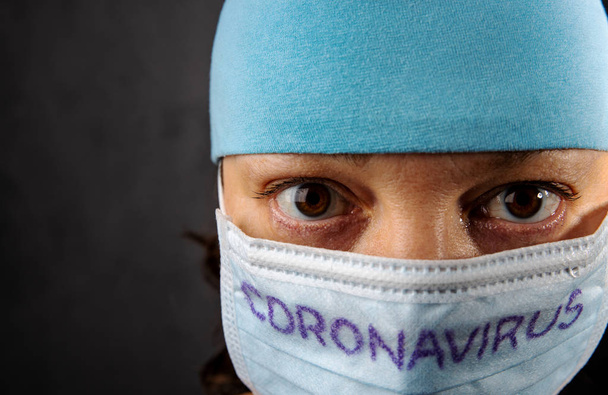 Muotokuva sairaanhoitajasta, jolla on lääketieteellinen naamio ja tekstisepelvaltimovirus mustalla taustalla. Coronavirus käsite. Pidä huolta terveydestäsi.
. - Valokuva, kuva