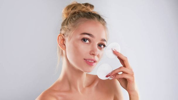 Healthy fresh girl removing makeup from her face with cotton pad. woman with a sponge wihte background cotton pad problem skin - 写真・画像