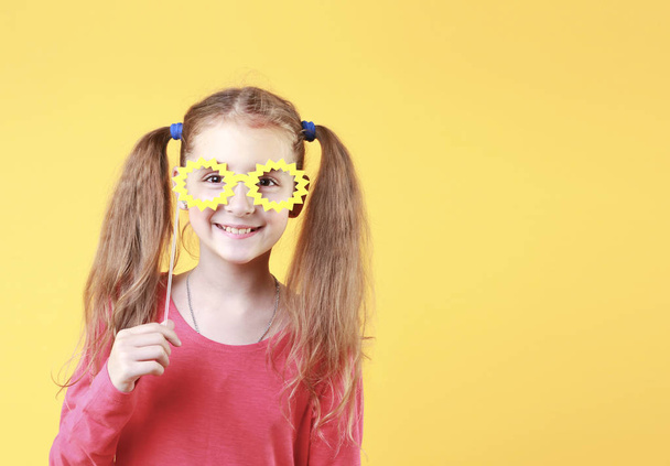 Caucasian child girl in yellow glasses happy face on empty space yellow background.Smiling positive kid. - Photo, image