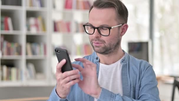 Giovane uomo in occhiali utilizzando smartphone
 - Filmati, video