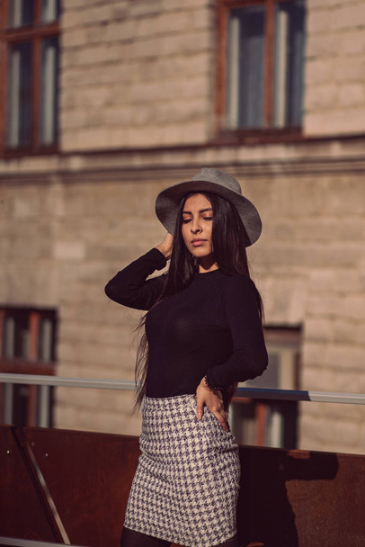 stylish girl in a hat with long hair posing against the backdrop of the building - Photo, Image