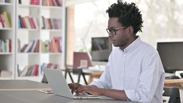 Afrikaanse man glimlachen op de camera tijdens het werken op laptop - Video