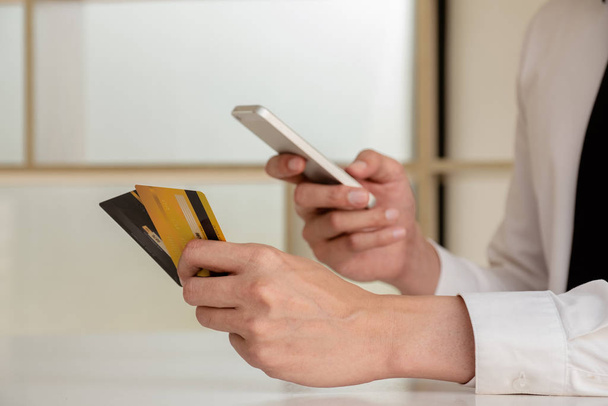 Les mains des hommes d'affaires détenant des cartes de crédit et des smartphones pour faire des achats en ligne et payer via Internet
. - Photo, image