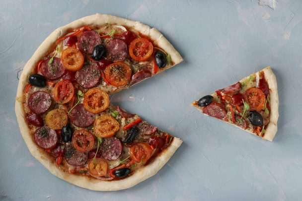 Pizza with a cut out piece on a light blue background, Closeup - Fotó, kép