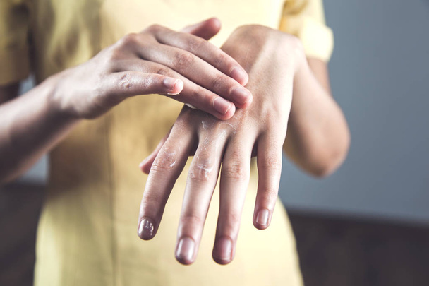 mujer aplicar crema en la mano sobre fondo oscuro
 - Foto, Imagen