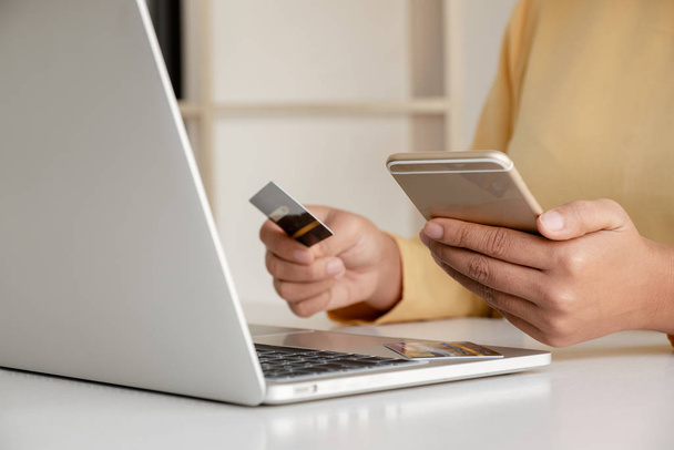 オンラインショッピングのためのクレジットカードやスマートフォンを保持し、インターネット経由で支払うビジネスの人々の手. - 写真・画像