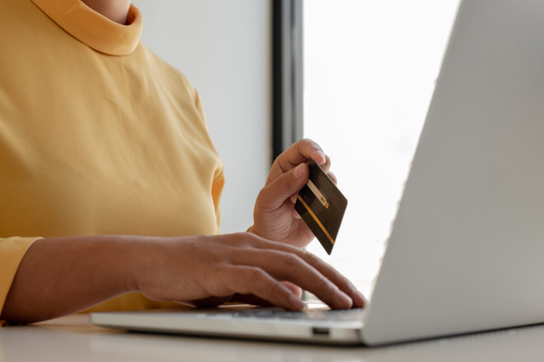 若い女性は、オンラインショッピングや支払いをインターネットにクレジットカードやラップトップを使用しています. - 写真・画像