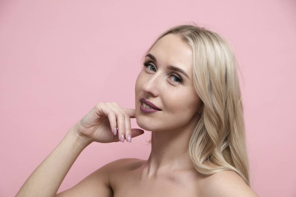 Beautiful blond woman with naked shoulders on pastel pink background. Beauty, cosmetics and skin care concept - Photo, Image