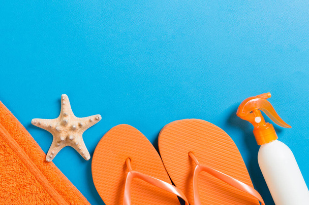 Top view of Beach flat lay accessories. sunscreen bottle with seashells, starfish, towel and flip-flop on Colored background with copy space. - Φωτογραφία, εικόνα