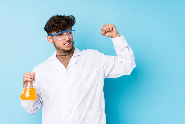 Young arab scientific man isolated raising fist after a victory, winner concept. - Photo, Image