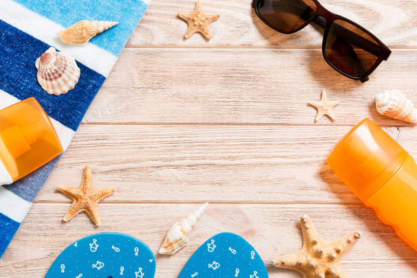 flip flops, straw hat, starfish, sunscreen bottle, body lotion spray on wooden background top view . flat lay summer beach sea accessories background, vacation concept. - 写真・画像