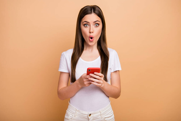 Portrait of astonished girl use cellphone read social network information impressed scream unbelievable unexpected wear good look outfit isolated over beige color background - Fotó, kép