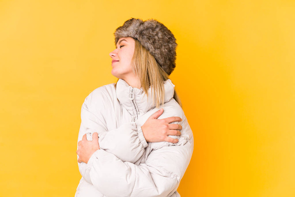 Young blonde caucasian woman wearing a winter clothes isolated hugs, smiling carefree and happy. - Photo, Image