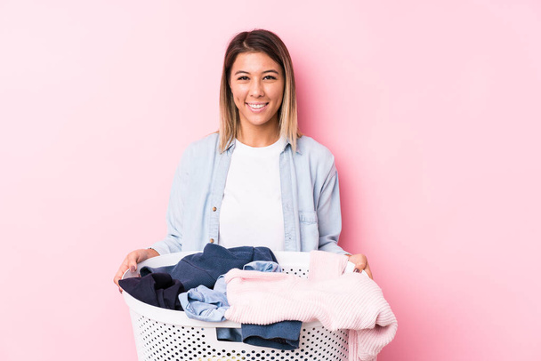 Young caucasian woman picking up a dirty clothes happy, smiling and cheerful. - Photo, Image