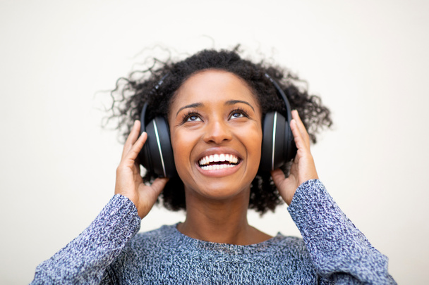 Nahaufnahme Porträt schöne junge schwarze Frau lächelt mit Kopfhörern vor weißem Hintergrund - Foto, Bild