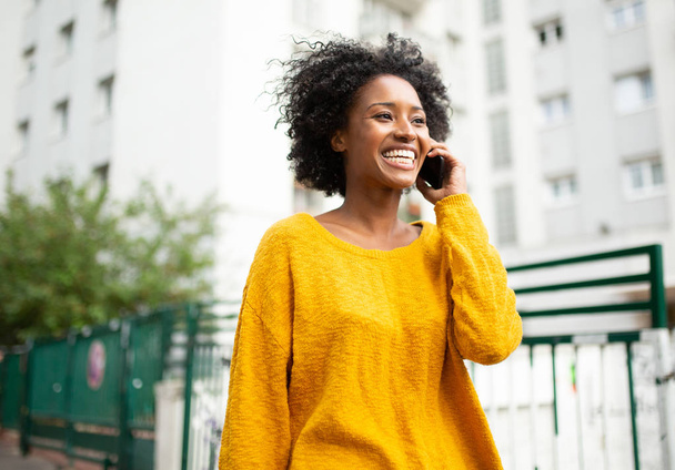 Portré vonzó fiatal fekete nő sétál a városban beszél mobiltelefonnal - Fotó, kép