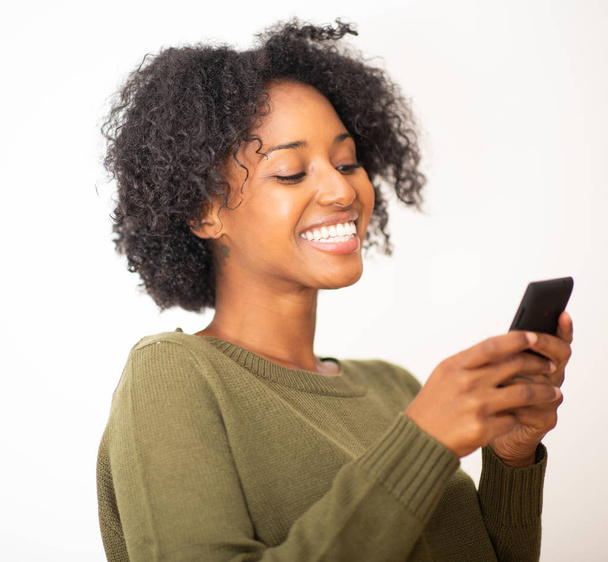 Крупным планом портрет улыбается молодой африканской женщины, использующей мобильный телефон на изолированном белом фоне
 - Фото, изображение