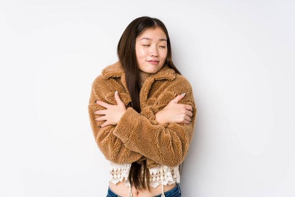 Joven mujer china posando en un fondo blanco abrazos aislados, sonriente despreocupado y feliz
. - Foto, imagen