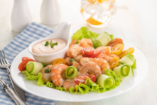 Grilled shrimp salad with fresh lettuce, cherry tomatoes and creamy sauce. Large portion on a white plate. Close up. Ready to eat. Selective focus. - Fotografie, Obrázek