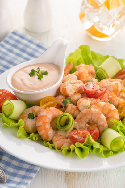 Grilled shrimp salad with fresh lettuce, cherry tomatoes and creamy sauce. Large portion on a white plate. Close up. Ready to eat. Selective focus. - Fotografie, Obrázek