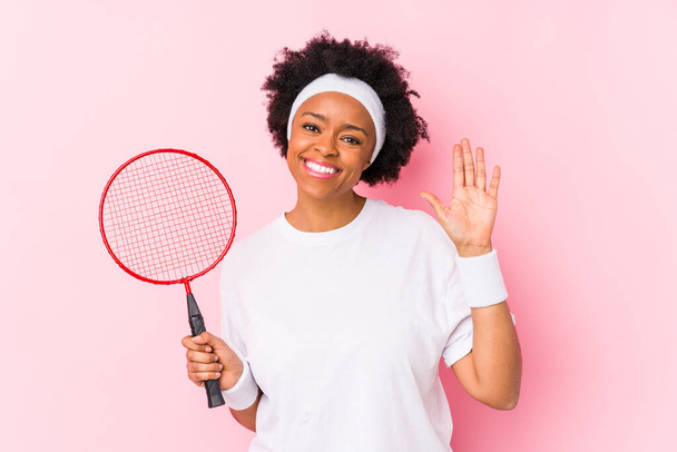 Badminton oynayan Afro-Amerikalı genç bir kadın, tebessüm ederek beş numarayı parmaklarıyla gösteriyordu.. - Fotoğraf, Görsel
