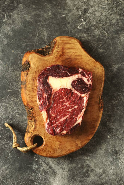 Verse rauwe rib eye steak op een houten plank. Biologisch voedsel.  - Foto, afbeelding