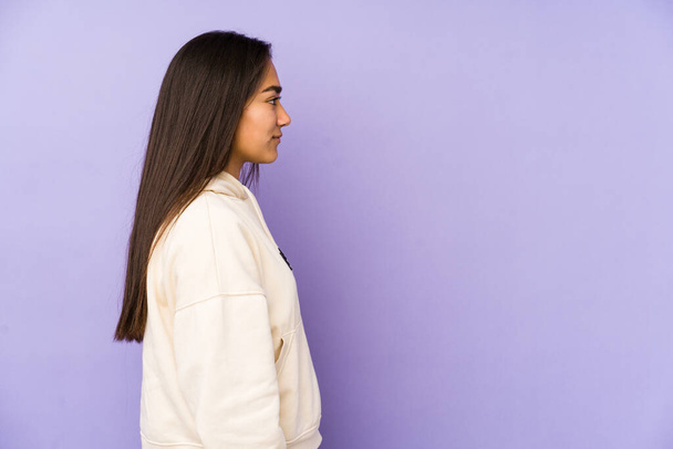 Young woman isolated on a purple background gazing left, sideways pose. - Foto, immagini