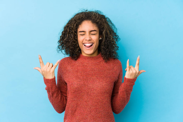 Junge Afroamerikanerin mit lockigem Haar zeigt Rock-Geste mit Fingern - Foto, Bild