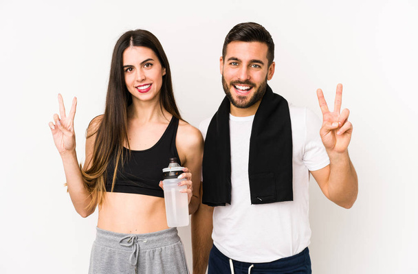 Junge kaukasische Fitness-Paar isoliert zeigt Siegeszeichen und lächelt breit. - Foto, Bild