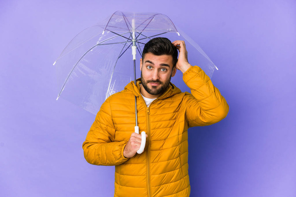 Young handsome man holding an umbrella isolated being shocked, she has remembered important meeting. - Photo, Image