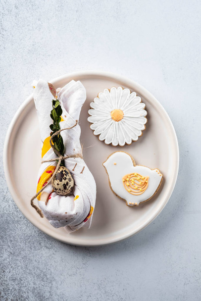 Table setting for the holiday of Easter. The photo shows white dishes, serving mat, Easter egg in a napkin. Napkin draped under rabbit ears. - Foto, Imagem