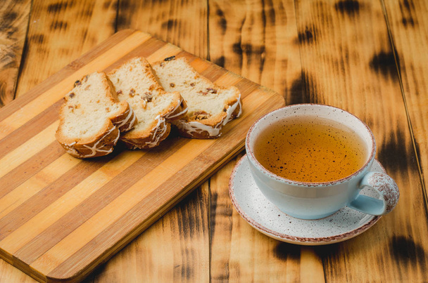 Breakfast with tea cup and pastries sliced on wooden board on a table. Selective focus - 写真・画像