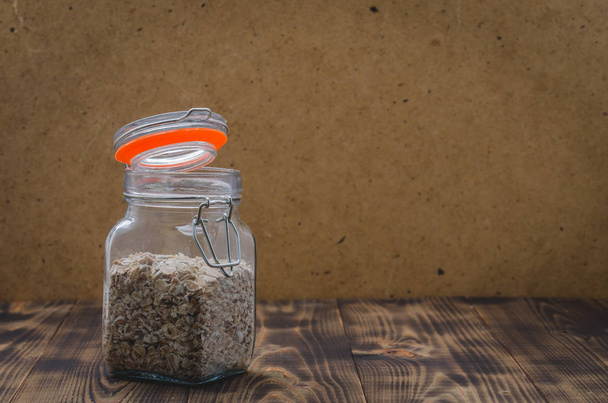 Homemade granola in open glass jar on a wooden table. Selective focus, copyspace - Fotó, kép