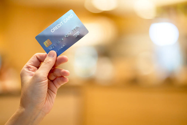 business shopping merchant ideas concept Close up of woman hand holding credit card for shopping with abstract blur mall background - Photo, image