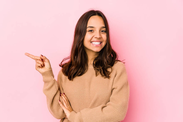 Young mixed race hispanic woman isolated smiling cheerfully pointing with forefinger away. - 写真・画像