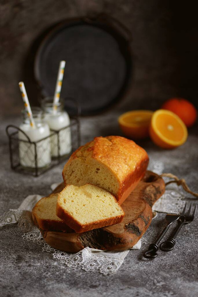Νόστιμο κέικ πορτοκάλι με γάλα σε ξύλινη σανίδα. Σπιτικό ψήσιμο. - Φωτογραφία, εικόνα
